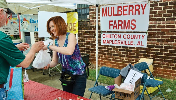 Amy Ballew with Mulberry Farms sells strawberries to a customer at Pepper Place market in Birmingham.